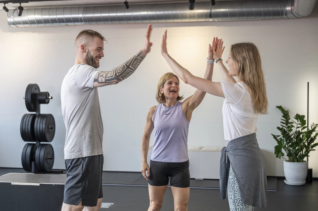 Drei Personen klatschen nach dem Training im hellen Studio von CHEETAH Health motiviert ab.