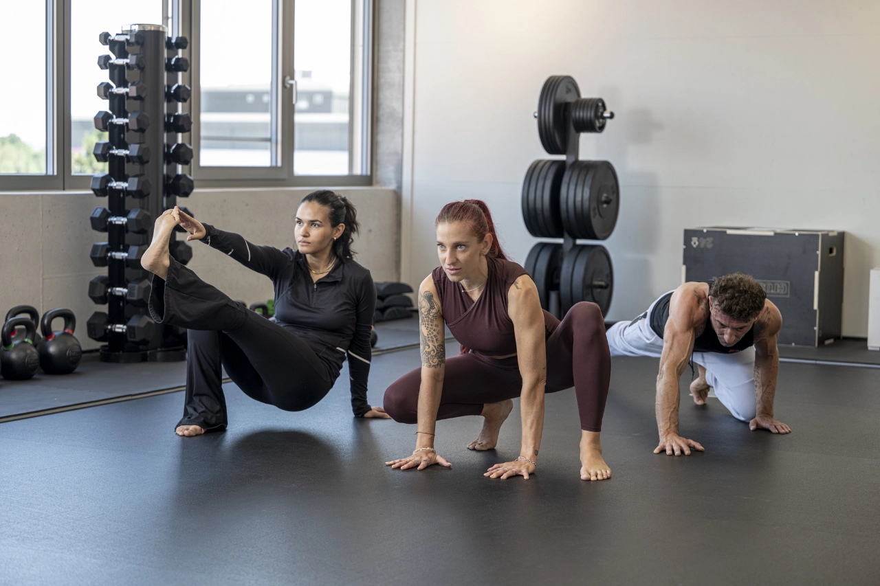 Drei Personen führen barfuß funktionelle Körpergewichts- und Mobilitätsübungen (Animal Flow) im hellen Trainingsraum von CHEETAH Health aus.